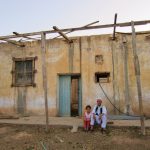 My daugher Layla sitting next to my father's oldest brother in front of the now abandoned earthen home in Gharyan