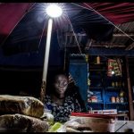 Aminatta uses an Indigo pay-as-you-go solar powered light to run her shop in Tombo village. (Pic: Tommy Trenchard/IRIN)