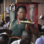 Madinah Nalukenge serves dishes to customers at her food stall, frequented by transport operators, that she owns on the edge of a bus terminal in Kampala. (Pic: AP Exchange)