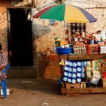 A woman and child sit in front of their stall in Sambizanga informal settlement outside the capital Luanda August on 28 2012. (Pic: Reuters)
