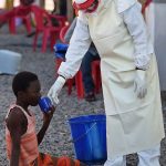 A health worker gives a drink to a young Ebola patient at the Kenama treatment centre run by the Red cross Society. (Pic: AFP)