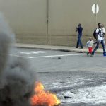 A foreign national walks with his children after clashes broke out between a group of locals and police on April 14 2015 in Durban. Hundreds of people have been displaced and forced to flee their homes this week. (Pic: AFP)